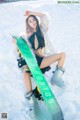 A woman sitting in the snow holding a snowboard.