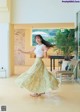 A woman in a white top and a yellow skirt dancing.