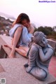 A woman sitting next to a statue of a buddha.