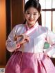 A woman in a pink and white hanbok poses for a picture.