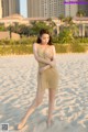 A woman in a gold dress standing on a sandy beach.