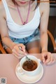 A woman sitting at a table with a cup of coffee.