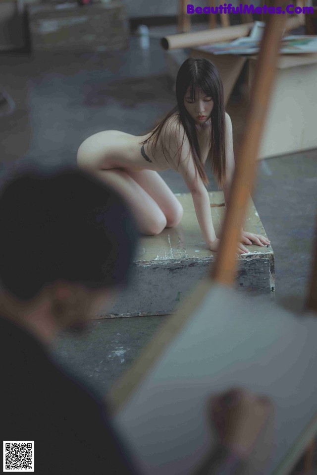 A naked woman sitting on top of a wooden box.